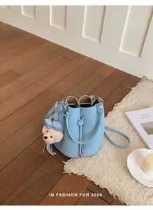 Light blue textured leather bucket bag with cute puppy charm shown on a stylish wooden floor