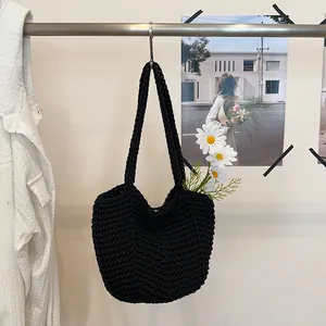 Detailed view of a black handmade crocheted shoulder bag with decorative white daisies