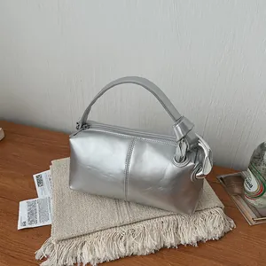 Sleek metallic silver pillow handbag with elegant top handle and minimalist design