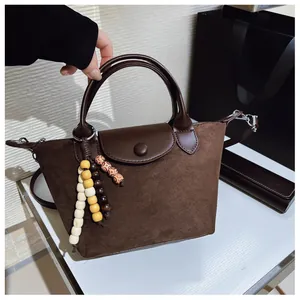 Détail d'un sac à main dumpling en daim marron avec un charme de perles colorées élégant