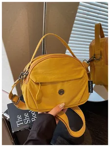 Primer plano de bolso de nylon amarillo con asa superior y correa de hombro ajustable