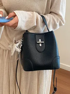 Élégant sac seau en cuir grainé noir avec un charm étoile argenté et un fermoir à tourniquet