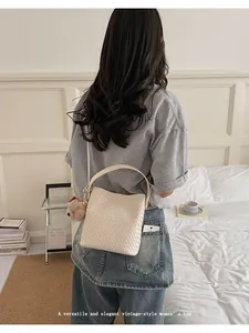 Lifestyle shot of a cream-colored vintage woven bucket bag for women with a cute teddy bear charm