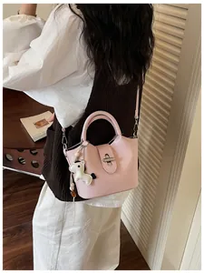 Sac seau rose élégant avec breloque cheval porté par un mannequin dans un cadre décontracté