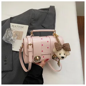 Close-up of pink polka dot crossbody bag with cute teddy bear charm