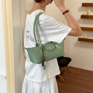 Vue détaillée d'un sac sous les bras vert minimaliste porté avec un T-shirt blanc décontracté.