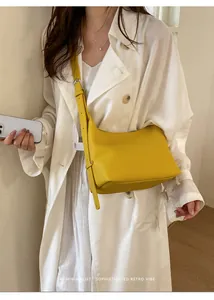 Detailed shot of the minimalist yellow leather underarm bag, showing soft texture and strap.