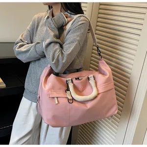 Vue détaillée d'un grand sac de voyage rose porté par un mannequin en intérieur