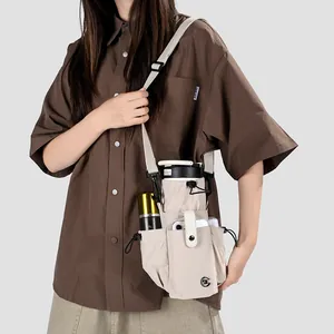 Vue détaillée d'un sac à bandoulière beige pour bouteille d'eau et téléphone porté par un mannequin