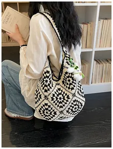 Dettaglio della borsa tote all'uncinetto in bianco e nero con ciondolo peluche