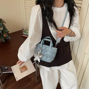Detail view of light blue mini bucket bag with silver star charm and quilted pattern