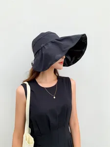 Profile view of a woman wearing a black wide-brimmed vinyl sun hat for UV protection