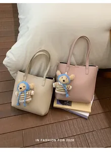 Detailed view of two elegant lychee grain leather tote bags with cute teddy bear charms