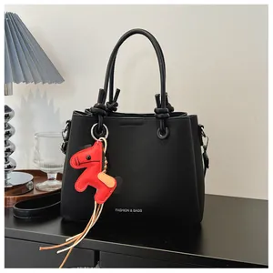 Elegant black textured leather bucket bag featuring a vibrant red horse charm detail
