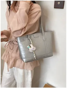 Close-up of silver tote bag featuring cute bunny pendant, ideal for daily commute.