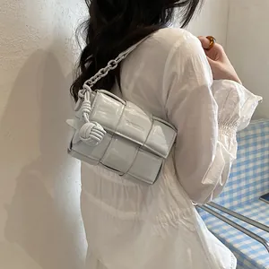 Light blue woven underarm bag with silver chain worn by woman in white shirt.