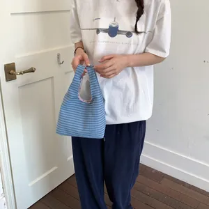 Detailaufnahme einer Frau mit einer blau karierten Freizeittasche in einem Innenraum