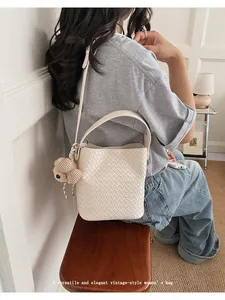 Elegant cream woven bucket bag with cute bear charm shown in a vintage commuting scene