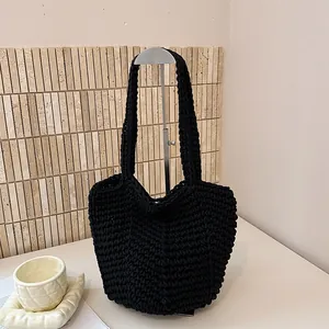 Detailed view of black chunky hand-knitted crochet shoulder bag on a display stand