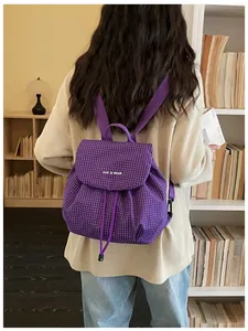 Detail shot of a purple grid casual backpack worn by a model in a library setting