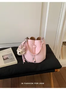 Detail view of a stylish pink textured leather bucket bag with a cute bear charm