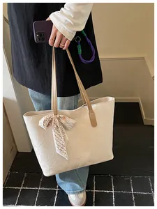 Detailed view of cream geometric embossed tote bag with decorative silk scarf accessory