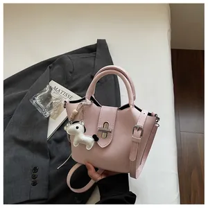 Vue détaillée du sac seau en cuir rose avec une décoration porte-clés petit poney blanc