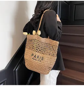 Elegante bolso tote de paja con texto de París llevado por una mujer en una escalera