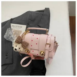 Close-up detail of a pink polka dot bag with a bear accessory and gold rotary lock