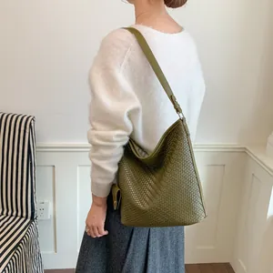 Gedetailleerd overzicht van een olijfgroene geweven leren emmertas met een retro hobo-stijl