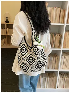 Vista posteriore di una grande borsa tote all'uncinetto bianco e nero con ciondolo peluche