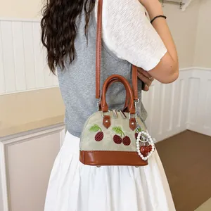 Elegante bolso bandolera tipo concha con bordado de cerezas y charm de perla