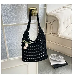 Bolso de ganchillo negro con colgante de tulipán colgado de un pomo de puerta.