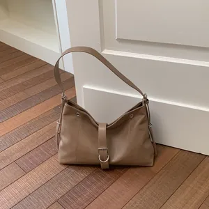 Close-up detail of a casual brown PU leather underarm tote bag with a decorative buckle.