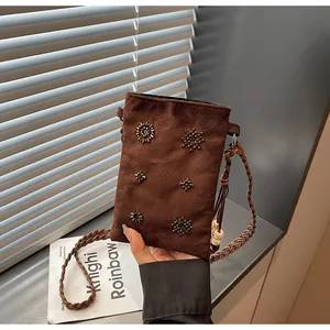 Close-up of brown suede crossbody phone bag featuring intricate beadwork patterns.
