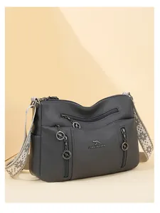 Detail view of grey multi-zippered crossbody bag with decorative kangaroo charms and woven strap.