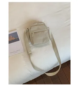 Detail view of a casual beige nylon crossbody phone bag styled with lifestyle props