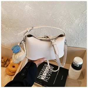 Close-up of cream pebble leather bucket bag with cute plush and pearl charms