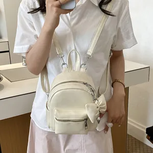 Detail eines cremefarbenen Mini-Rucksacks mit Schleifenanhänger