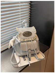 Detail showing the lace trim and decorative metal plaque on the light blue backpack