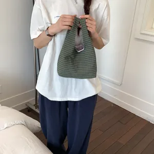 Nahaufnahme einer grünen karierten Handtasche, die von einem Model gehalten wird