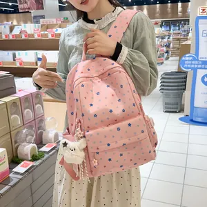 Side view of a pink backpack with star prints and a plush bear pendant accessory