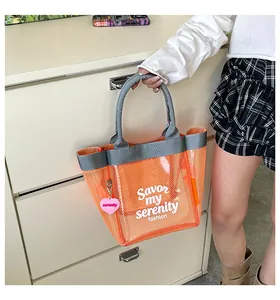 Modern vibrant orange mesh bucket handbag held against a minimalist white dresser