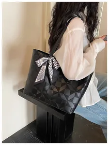 Close-up of black geometric quilted tote bag with silk scarf accessory on model shoulder