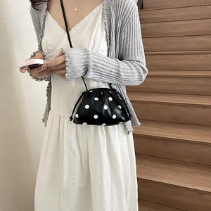 Stylish black and white polka dot crossbody bag worn with a casual summer dress and cardigan