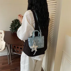 Lifestyle view of a light blue textured bucket bag with a silver star charm accessory.