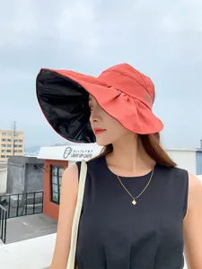 Woman wearing fashion orange sun hat featuring wide brim and black UV protection lining