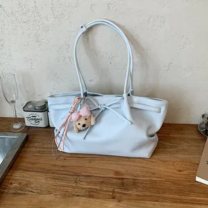 Zachte lichtblauwe kunstlederen tas met elegante knoop en pluchen puppybedeltje.