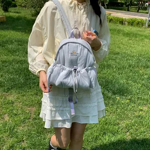 Detalle de una mochila gris claro con logo de oso para uso diario al aire libre