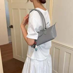 Élégant sac à bandoulière gris minimaliste avec breloque en perles colorées sur un mannequin